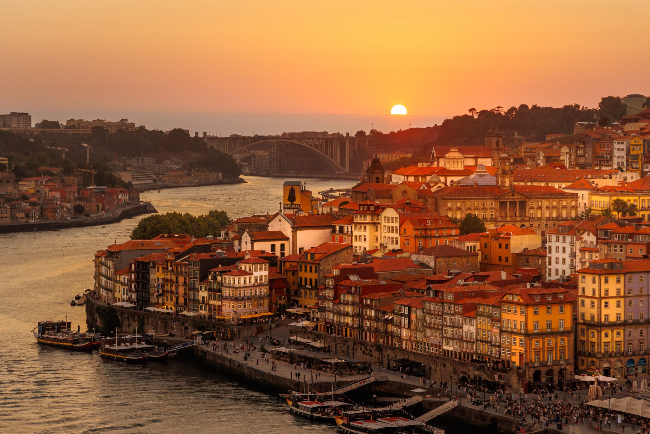 A golden, panoramic sunset view over Cais da Ribeira and Porto's historic center